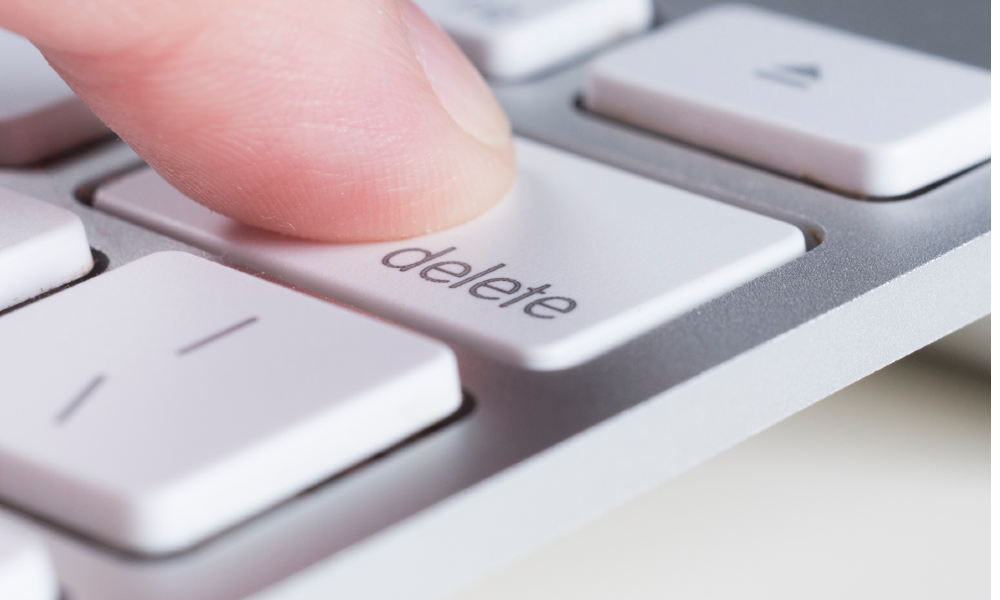 A finger presses the delete key on a computer keyboard, signifying file deletion on a solid-state drive (SSD).